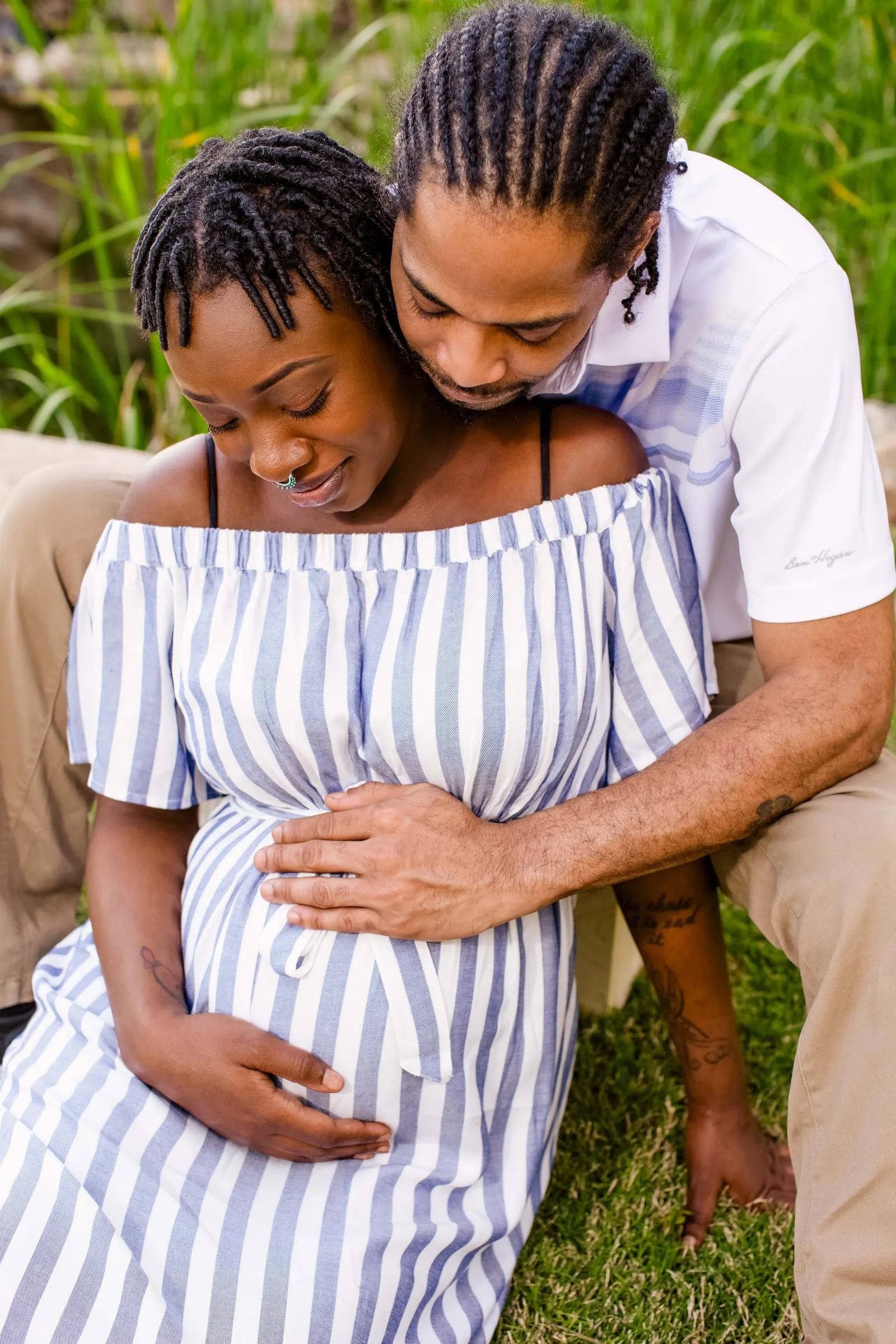 An expectant couple in a quiet embrace, her hands resting on her belly.