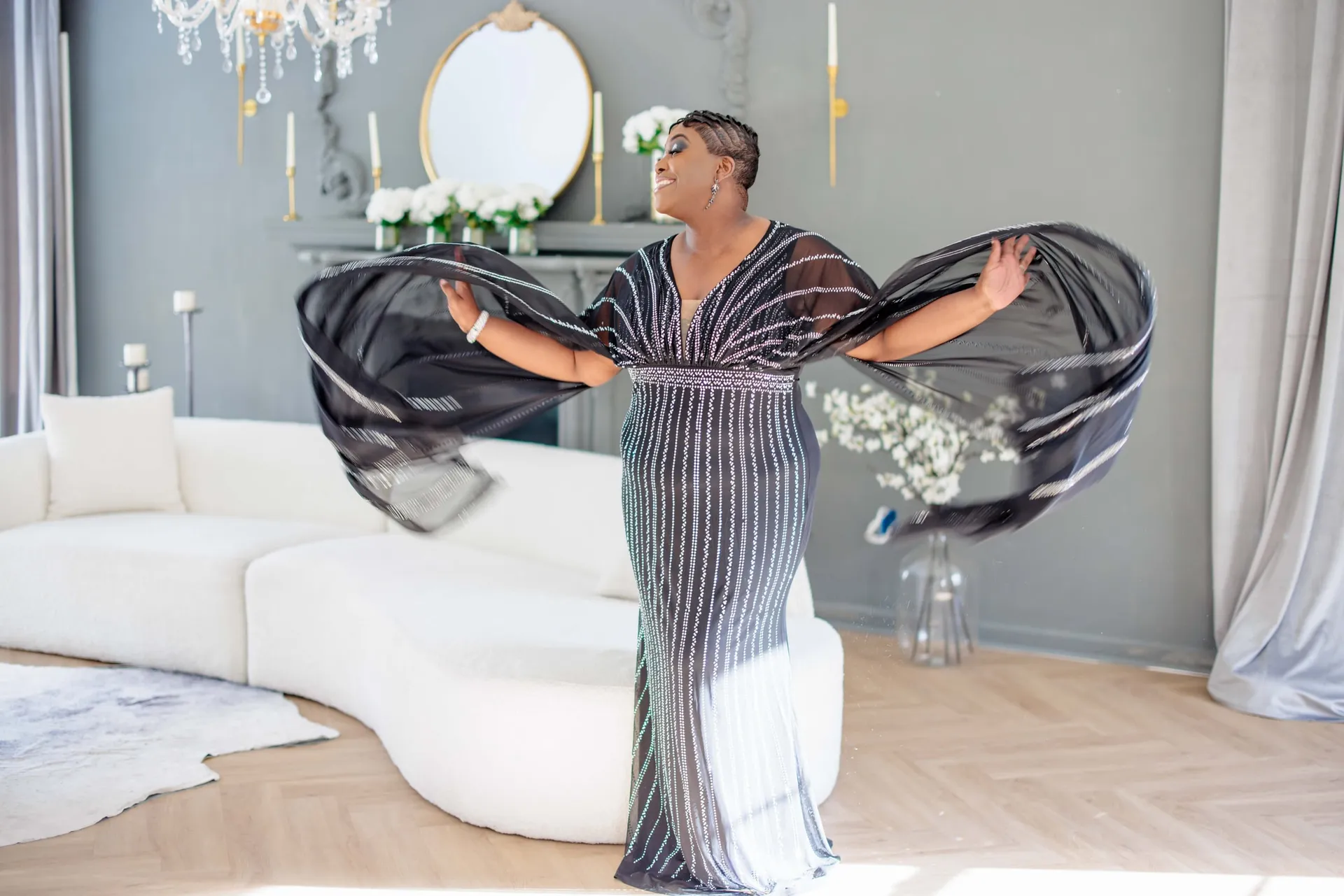 A woman twirling a striped black gown in a bright styled lounge with a gilded mirror.
